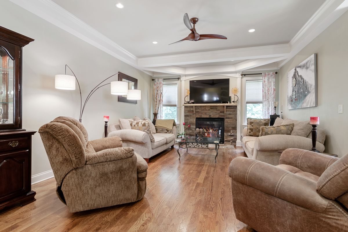 Living room with a smooth, freshly painted ceiling, crown molding, and a ceiling fan